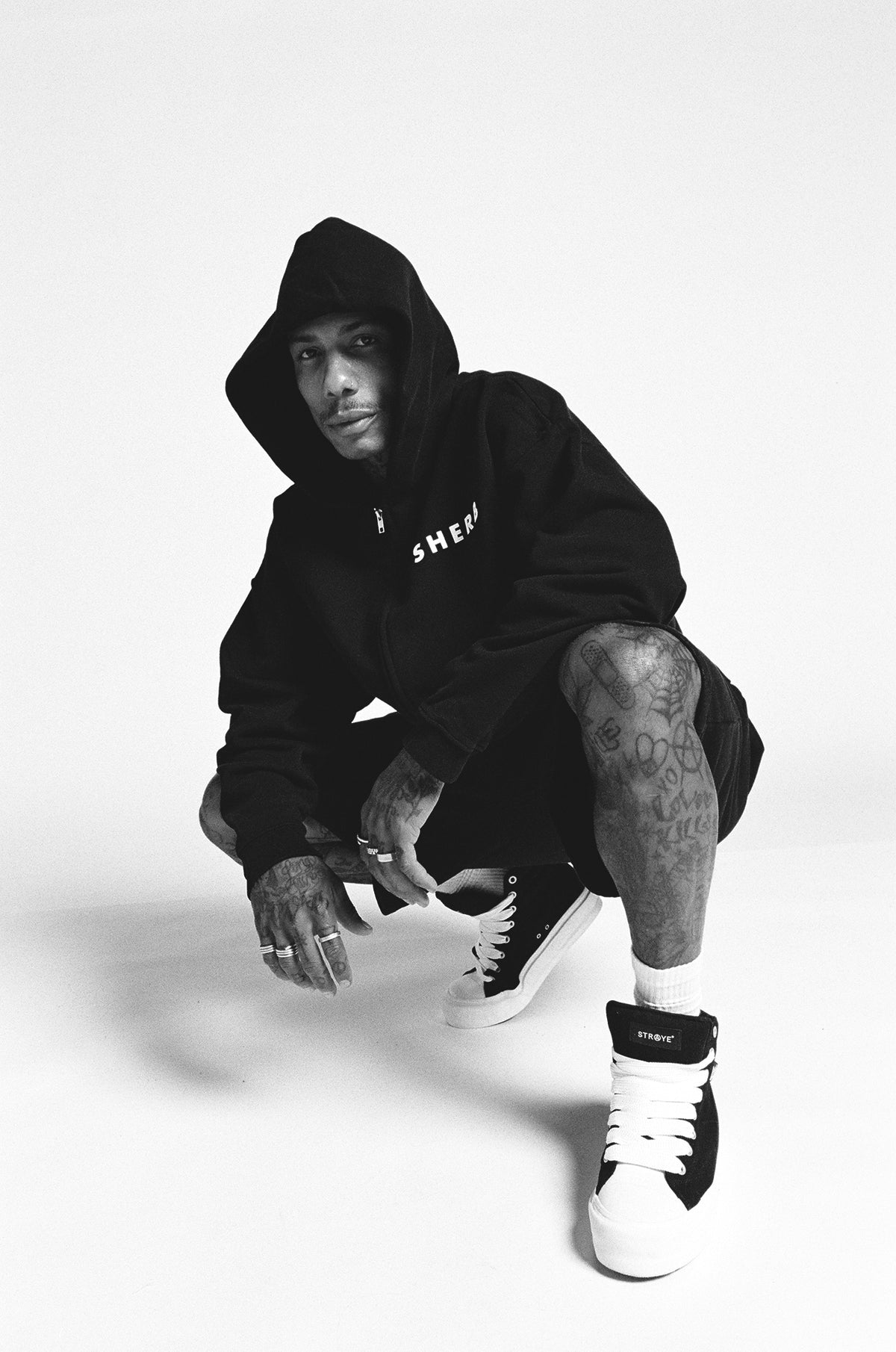 Black SHERB zip hoodie and shorts in a crouched monochrome portrait